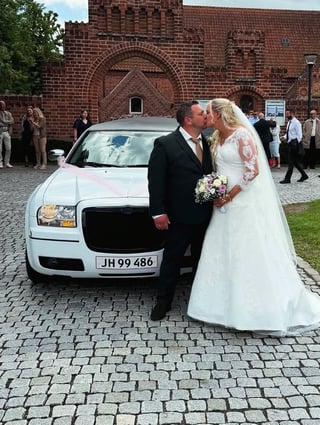 Brudepar foran hvid limousine ved kirke